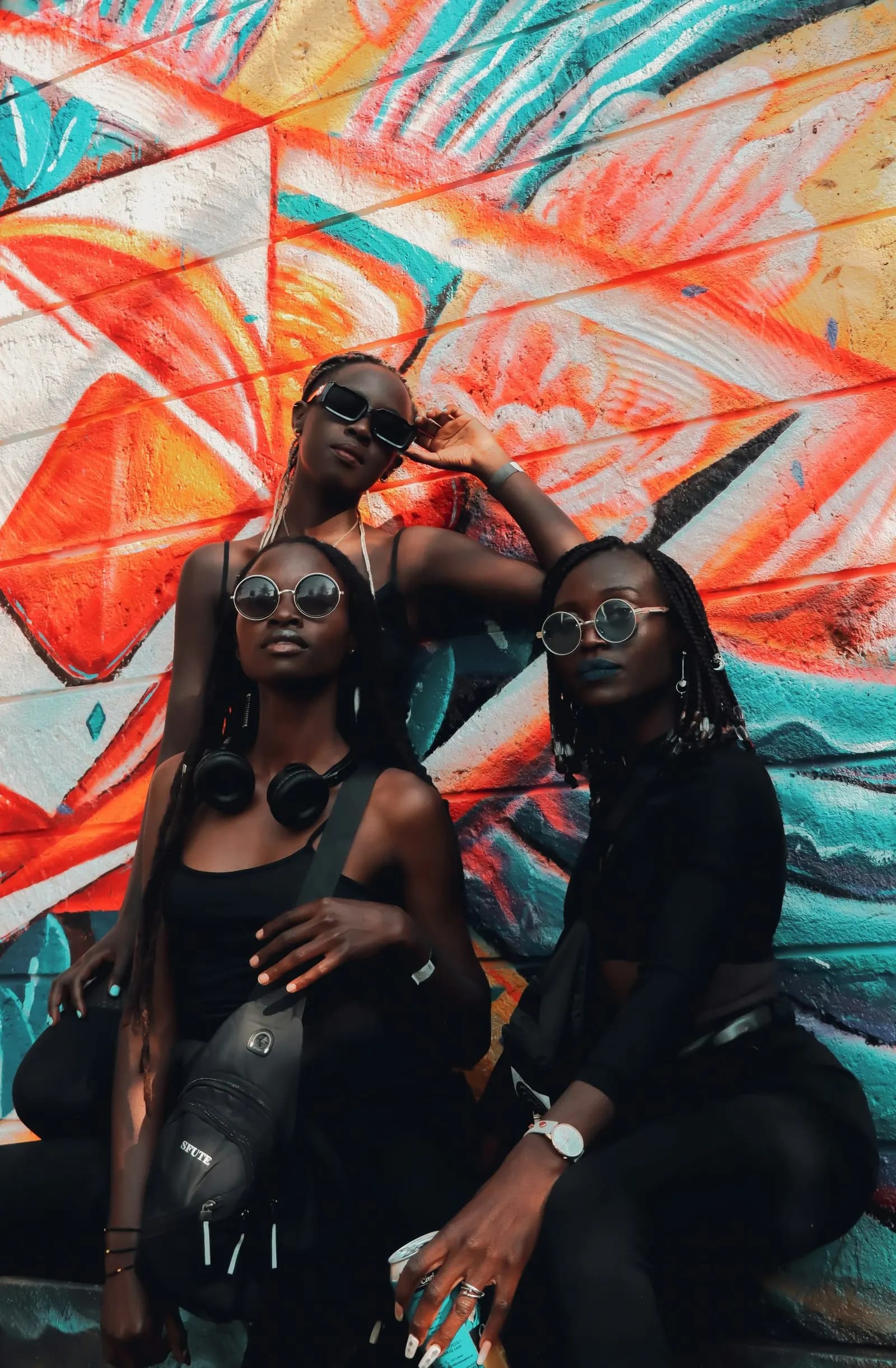 Three stylish women in front of a colourful mural